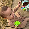 toddler, child, toy, green_block, sidewalk, stroller, sneaker, outdoor, grass, concrete, happy, playing, baby, clothing, person, footwear, daylight, casual, expression, sitting