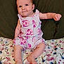 baby, infant, romper, fish_pattern, floral_blanket, cushion, smile, cheeks, barefoot, skin, arm, leg, head, sitting, indoors, cute, child, person, clothing, fabric