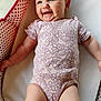 baby, infant, smiling, onesie, floral_pattern, polka_dots, pink, white, soft_surface, lying_down, cute, happy, child, skin, arm, face, head, legs, indoors, portrait
