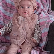 Payton joined the competition — help win amazing prizes! baby, infant, child, portrait, sitting, smiling, wide_eyed, pink_outfit, headband, bow, fluffy_vest, blanket, striped_blanket, couch, socks, clothing, indoors, cozy, face, photography