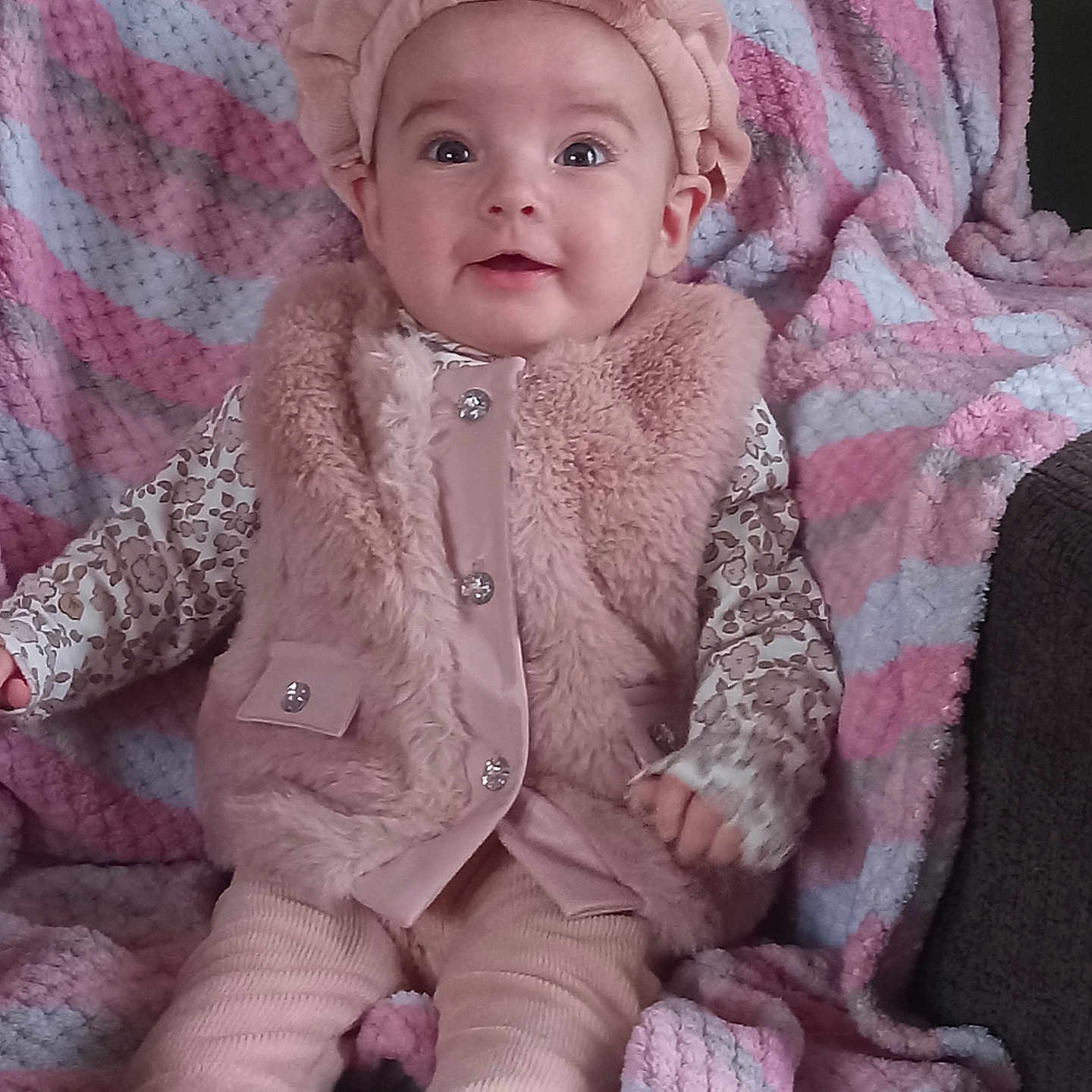 Payton joined the competition — help win amazing prizes! baby, infant, child, portrait, sitting, smiling, wide_eyed, pink_outfit, headband, bow, fluffy_vest, blanket, striped_blanket, couch, socks, clothing, indoors, cozy, face, photography