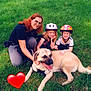 woman, child, dog, grass, outdoor, helmet, smiling, happy, pet, animal, nature, family, playing, casual_clothing, red_hair, greenery, summer, love, heart_emoji, posing