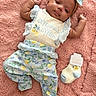 adorable, baby, blanket, bow, child, clothing, cute, floral, headband, indoors, infant, lemon, lying_down, patterned_pants, pink, portrait, relaxed, sock, soft_texture, tag
