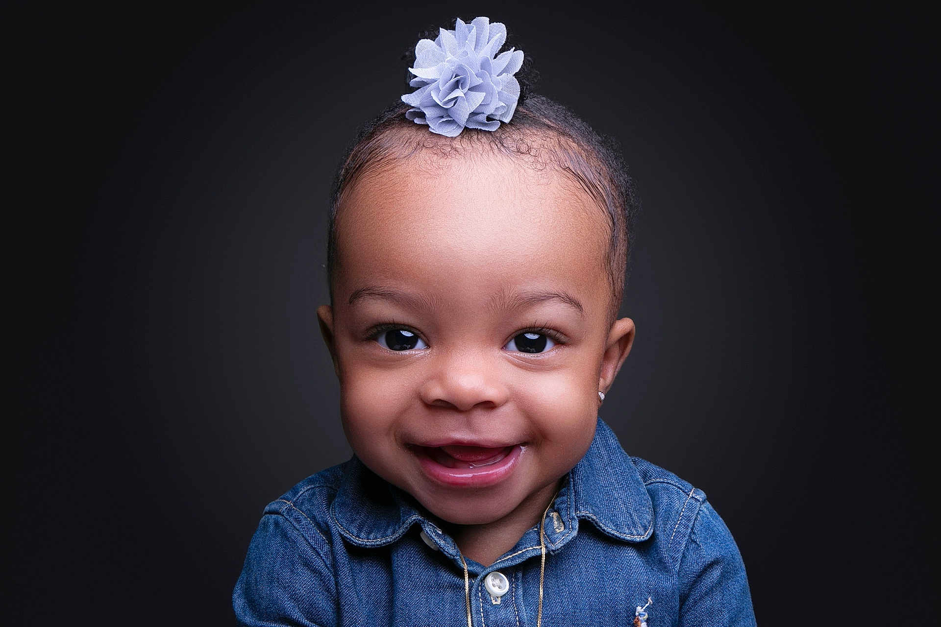 Camryn is registered to the contest to win money with this photo: toddler, child, smiling, portrait, denim_shirt, flower_accessory, cute, happy, face, headshot, studio, dark_background, jewelry, person, young_child, innocence, closeup, fashion, baby, expression