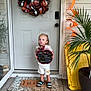 child, concrete, curious, decoration, door, face, footwear, green, halloween, house, orange, plant, porch, shirt, shorts, sign, welcome_mat, window, wreath, yellow