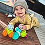 baby, child, toy, caterpillar_toy, floor, wooden_floor, hat, knit_hat, yellow_outfit, smiling, happy, indoor, playpen, carpet, cute, infant, toddler, person, playtime, colorful_toy