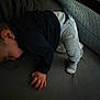 child, sleeping, couch, clothing, pants, socks, hand, resting, indoor, furniture, dark_clothing, light_pants, striped_socks, person, young_child, relaxing, home, blurred, cozy, lying_down