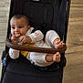 baby, child, stroller, toy, wooden_toy, blanket, knitwear, feet, hands, face, indoor, floor, comfort, curious, infant, person, clothing, relaxing, seat, casual