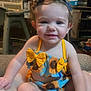 Brooklyn is registered to the contest to win money with this photo: toddler, child, smile, sunflower, headband, bow, clothing, sitting, indoors, couch, happy, baby, person, portrait, cute, skin, face, hand, foot, furniture