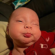 Vaela is registered to the contest to win money with this photo: baby, infant, face, expression, red_clothing, onesie, cheeks, pout, indoor, portrait, cute, child, skin, head, eyes, mouth, person, newborn, sleepy, funny