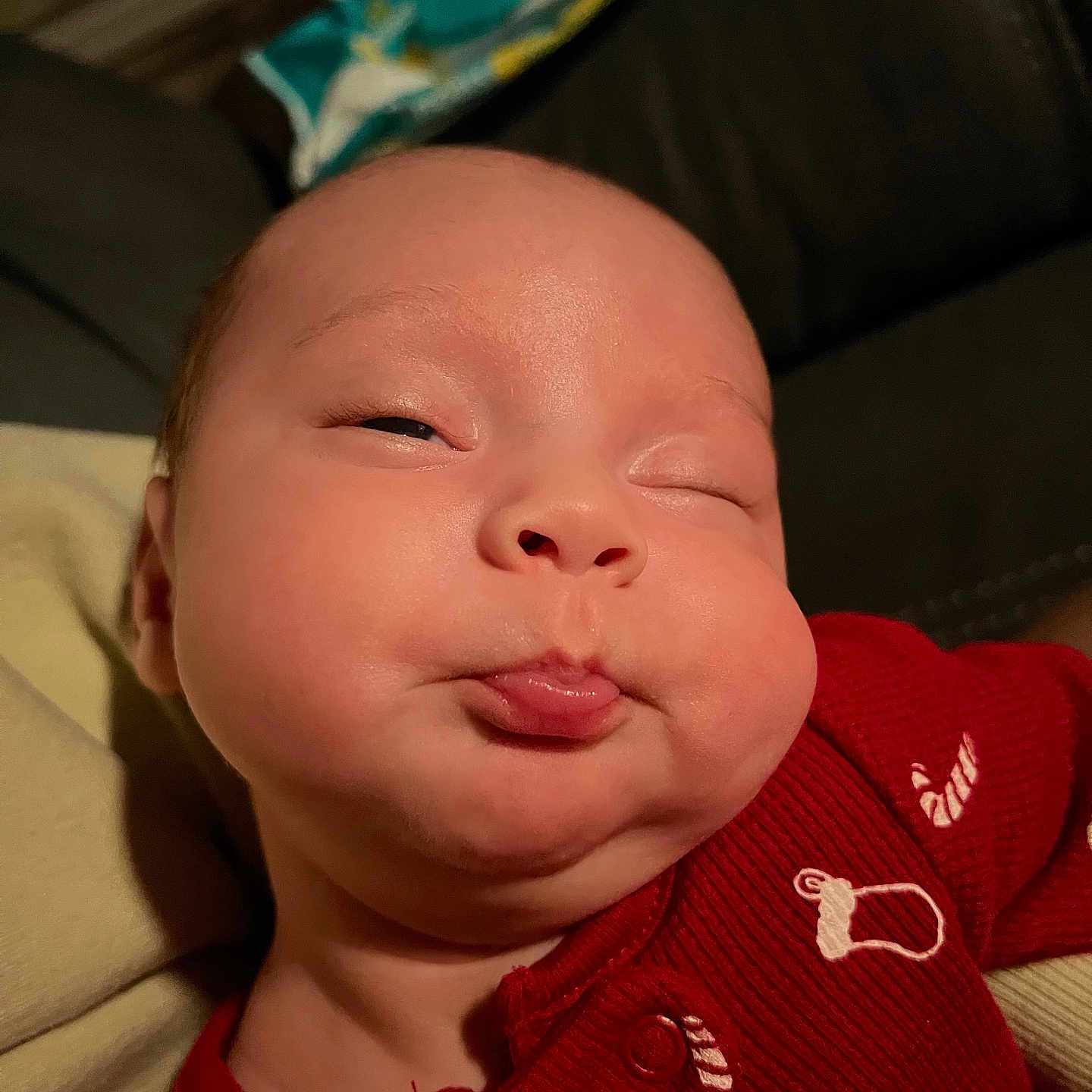 Vaela is registered to the contest to win money with this photo: baby, cheeks, child, cute, expression, eyes, face, funny, head, indoor, infant, mouth, newborn, onesie, person, portrait, pout, red_clothing, skin, sleepy