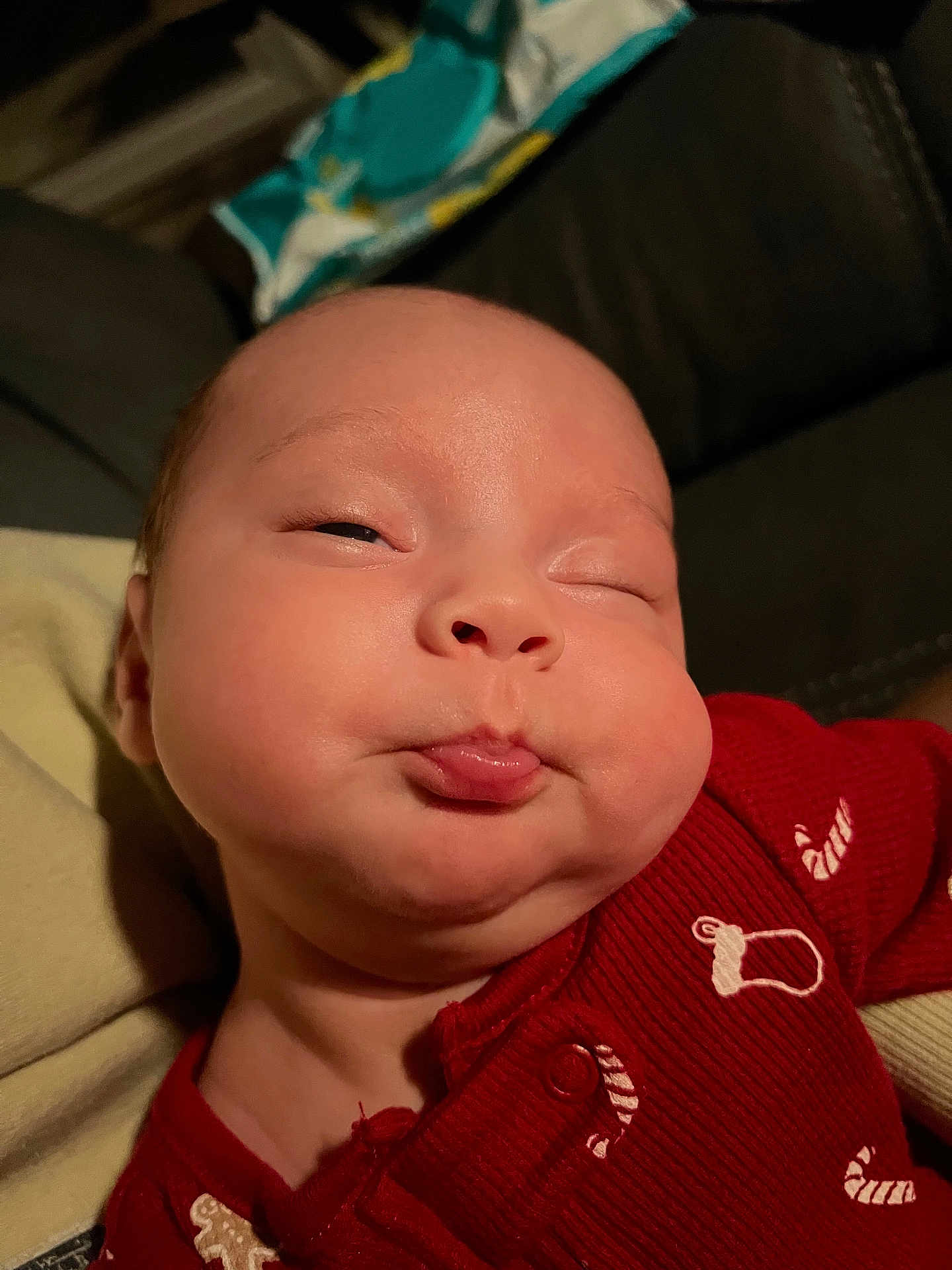 Vaela is registered to the contest to win money with this photo: baby, infant, face, expression, red_clothing, onesie, cheeks, pout, indoor, portrait, cute, child, skin, head, eyes, mouth, person, newborn, sleepy, funny