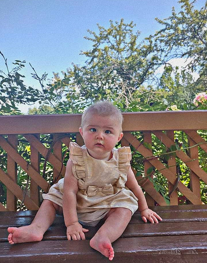 Jenevieve is registered to the contest to win money with this photo: baby, baby_toddler_clothing, child, fun, grass, happy, hardwood, leisure, mammal, outdoor_furniture, people_in_nature, person, plant, shorts, sitting, sky, standing, toddler, tree, vertebrate