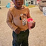 Jannah is registered to the contest to win money with this photo: child, toddler, indoor, carpet, cup, hair_buns, red_beads, sweater, dog_design, pants, black_shoes, toy_kitchen, toy_horse, living_room, laundry_basket, sofa, earrings, person, cute, playful