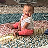 baby, barefoot, carpet, child, clothing, happy, home, indoors, infant, patterned_blanket, photography, pink_pants, play_mat, playroom, portrait, sitting, smiling, storage_bins, toy_storage, white_shirt