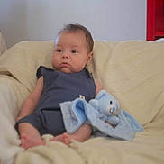 Daniel a rejoint le concours — aidez-le/la à gagner de superbes lots ! baby, blanket, blue_toy, calm, child, couch, cute, expression, face, furniture, indoor, infant, person, plush, resting, romper, seated, soft_toy, stuffed_toy, young
