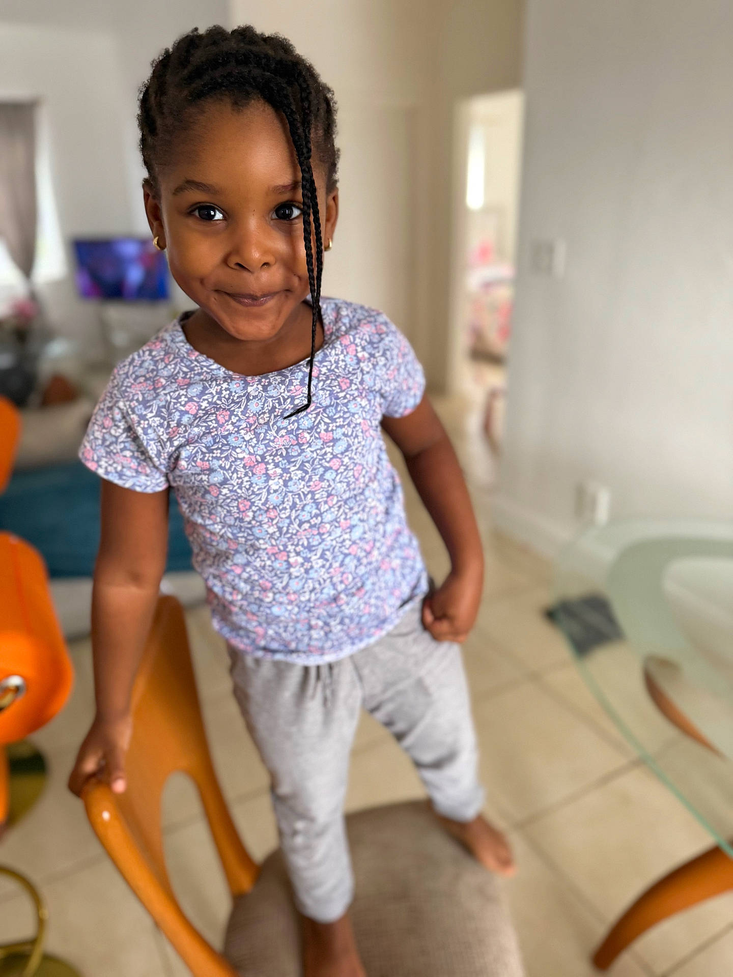 Rose-Renee is registered to the contest to win money with this photo: background, barefoot, braids, casual_clothing, chair, child, floor, furniture, girl, hand, happy, home, indoor, person, portrait, smiling, standing, television, tile_floor, young
