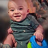 baby, smiling, child, toy, colorful, hand, face, blue, green, clothing, short_sleeve, sitting, cute, infant, happy, indoors, skin, portrait, play, young