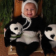 Hadryel participe au concours pour gagner de l'argent avec cette photo : baby, black_and_white, child, cozy, cuddly, cute, greenery, happy, headwear, indoor, infant, nature, panda_costume, playful, plush_toy, portrait, sitting, smile, soft_texture, toy