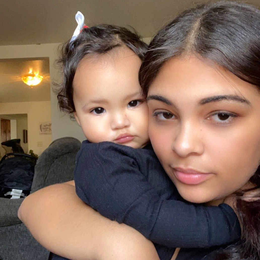 Row is registered to the contest to win money with this photo: arm, baby, black_clothing, child, closeup, couch, cute, expression, face, furniture, hair, home, hug, indoor, light, living_room, person, portrait, skin, woman