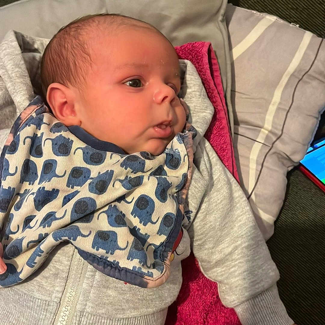 Owen participe au concours pour gagner de l'argent avec cette photo : baby, bib, blanket, child, clothing, cute, elephant_pattern, face, gray_outfit, indoors, infant, lying_down, newborn, person, pillow, resting, sleepwear, soft_texture, toddler, warm