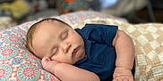 Bryce is registered to the contest to win money with this photo: baby, sleeping, infant, pillow, pattern, blue_shirt, hand, face, closeup, soft_light, indoors, blanket, resting, peaceful, skin, child, cute, cozy, portrait, relaxation