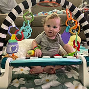 Bryce joined the competition — help win amazing prizes! baby, child, toys, play_gym, colorful, blanket, floral, indoor, couch, living_room, infant, cute, smiling, seated, soft_lighting, person, head, feet, clothing, playtime