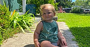 Bryce is registered to the contest to win money with this photo: toddler, child, sidewalk, grass, plants, greenery, tank_top, outdoor, sunlight, blue_sky, portrait, sitting, cute, happy, nature, daytime, casual_clothing, shoes_off, baby, smile