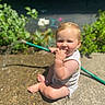 Bryce joined the competition — help win amazing prizes! baby, child, garden_hose, water, outdoor, sunlight, concrete, greenery, flower, sitting, curious, cute, summer, nature, infant, person, sunny, hand, foot, playful
