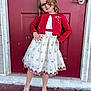 child, girl, dress, cardigan, glasses, curly_hair, silver_shoes, door, red_door, porch, smile, pose, happy, fashion, outdoor, flower_pattern, footwear, person, young, standing
