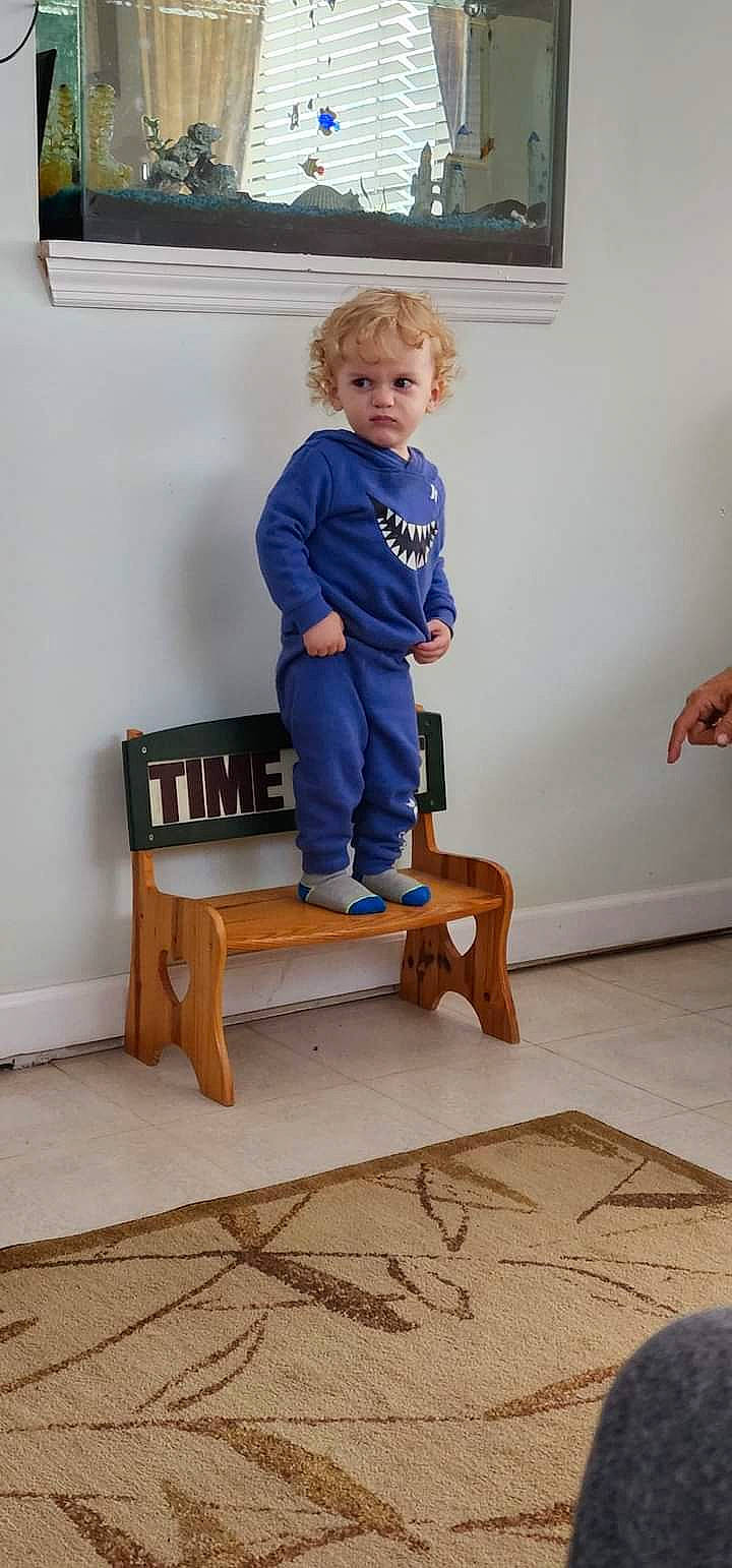 Kolten joined the competition — help win amazing prizes! baby_toddler_clothing, chair, comfort, electric_blue, floor, flooring, furniture, hardwood, house, joint, knee, leg, person, room, sitting, sleeve, standing, t_shirt, table, toddler