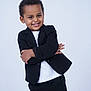 child, smile, black_suit, white_shirt, posing, confident, happy, portrait, studio, curly_hair, young, fashion, formal, person, cute, background, standing, arms_crossed, expression, studio_lighting