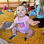 baby, child, corn, corn_pit, indoor, barn, play, smile, people, group, clothing, socks, wooden_beams, fun, happy, reaching, sitting, person, event, casual