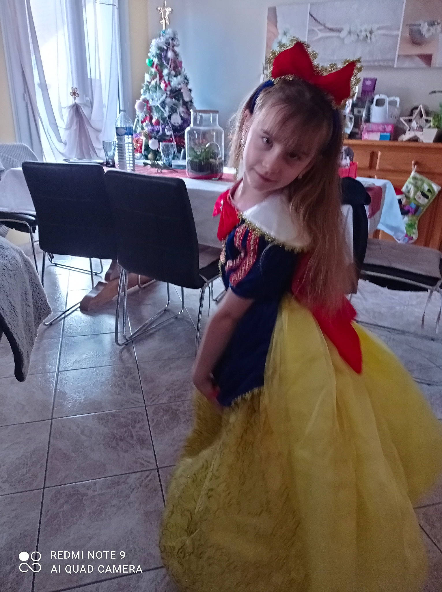 Pauline participe au concours pour gagner de l'argent avec cette photo : christmas_decoration, christmas_ornament, christmas_tree, curtain, dress, embellishment, event, fashion_design, flooring, formal_wear, furniture, gown, happy, lighting, ornament, person, photograph, smile, snapshot, toddler