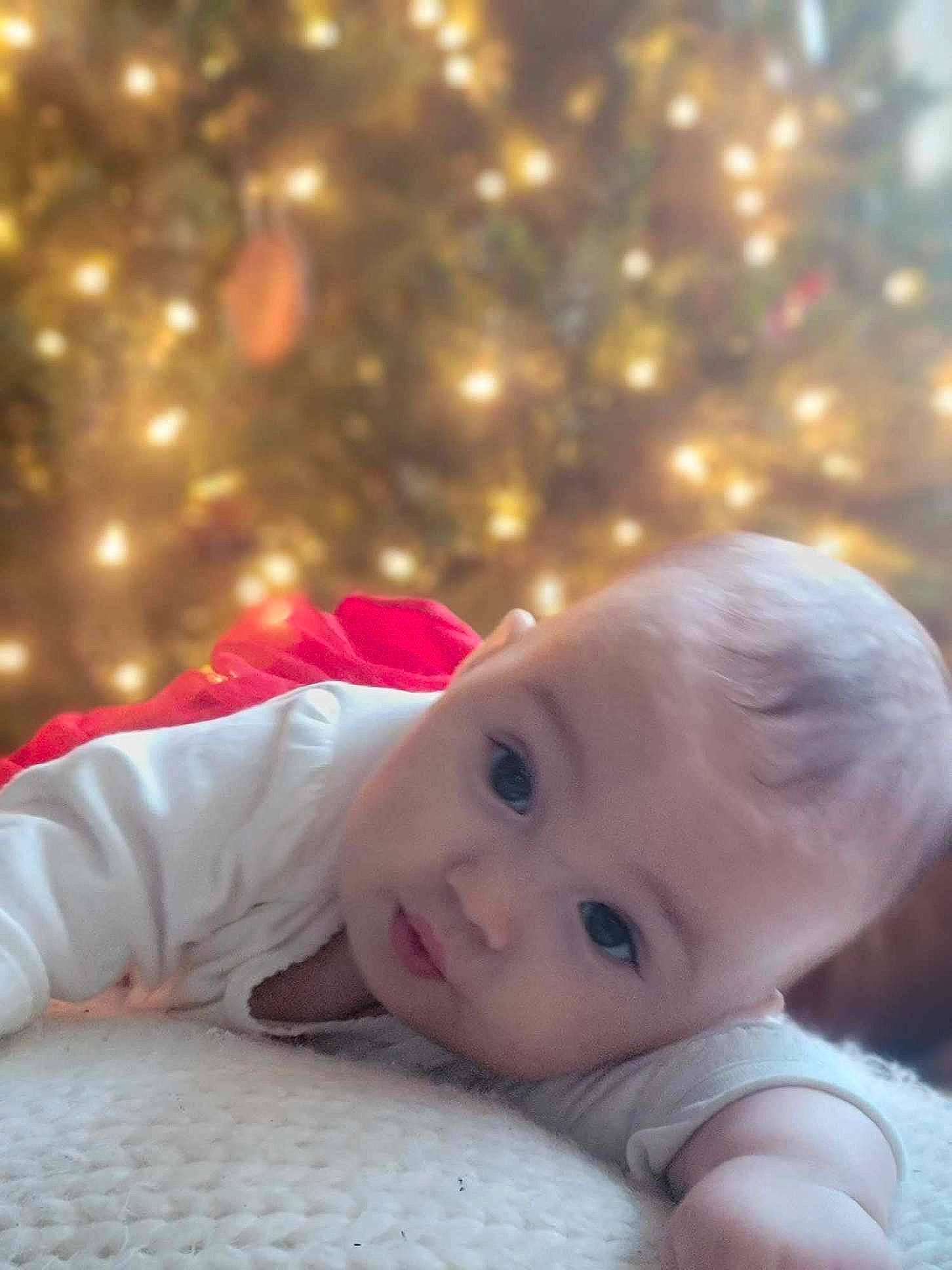 Ruby is registered to the contest to win money with this photo: baby, baby_toddler_clothing, cheek, chin, christmas, christmas_decoration, christmas_ornament, christmas_tree, eye, facial_expression, fun, hairstyle, happy, head, holiday, human_body, ornament, person, plant, skin