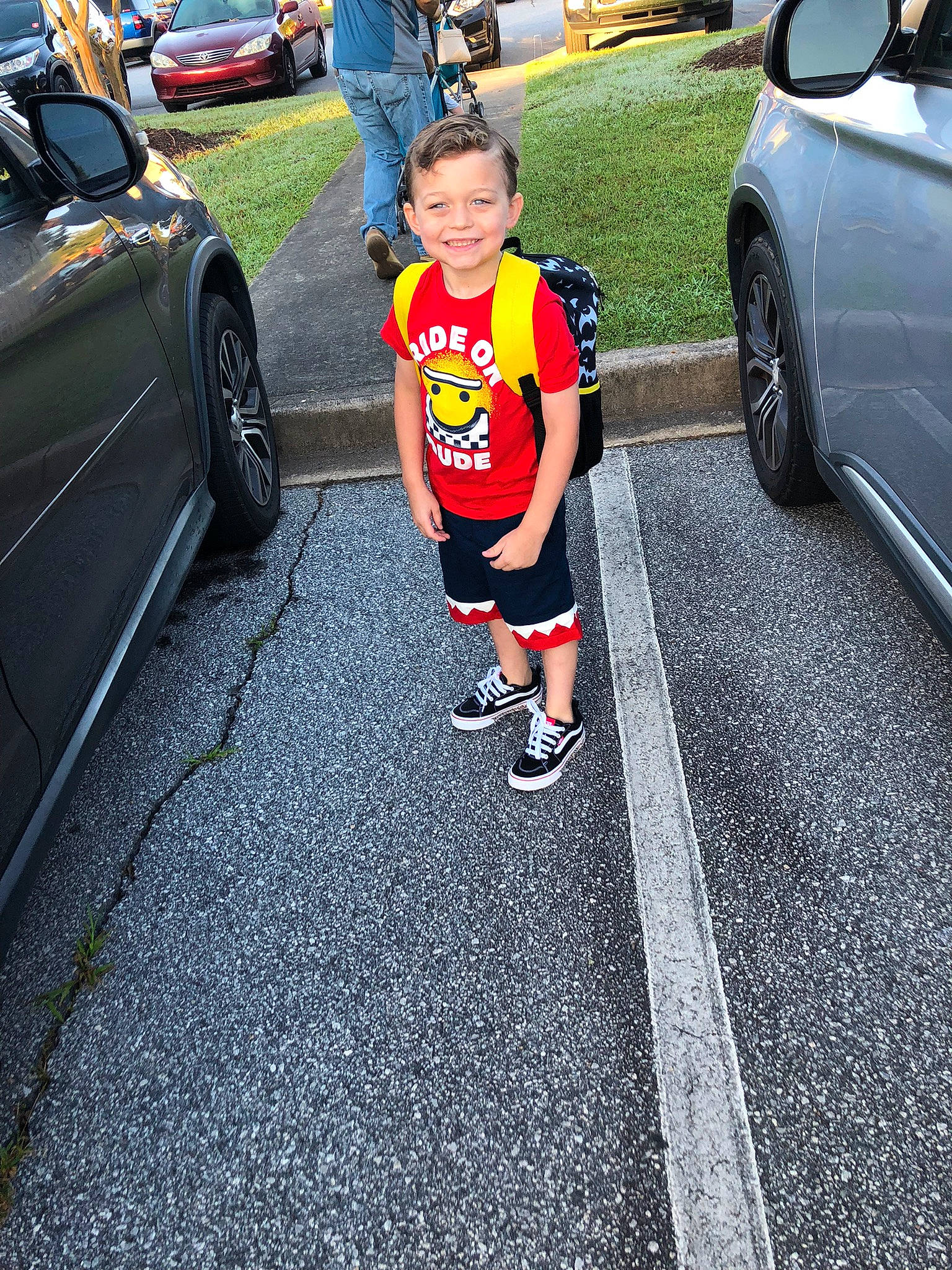 Brantlee is registered to the contest to win money with this photo: asphalt, automotive_design, automotive_exterior, automotive_lighting, automotive_tire, car, joy, land_vehicle, leg, motor_vehicle, parking, person, plant, road_surface, rolling, shorts, sidewalk, tire, toddler, vehicle