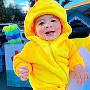 Dijoa is registered to the contest to win money with this photo: baby, child, costume, yellow, chick, hood, smiling, teeth, hand, adult, outdoor, balloons, party, cute, face, person, joyful, bright, festive, clothing