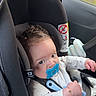 baby, black, bracelet, car_interior, car_seat, child, curly_hair, cute, expression, hand, indoors, infant, pacifier, portrait, safety, seatbelt, teether, travel, white_clothing, young_child