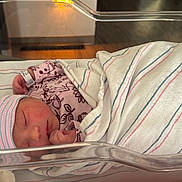 Renatta is registered to the contest to win money with this photo: baby, bassinet, bed, blanket, blue, cute, hat, hospital, hospital_room, infant, newborn, nursery, peaceful, person, pink, sleep, sleeping, striped, swaddled, wrapped
