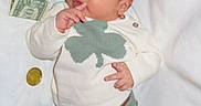 Elijah is registered to the contest to win money with this photo: baby, barefoot, child, clothing, coins, curious, currency, cute, date_stamp, dollar_bills, green_clover, indoors, infant, lying_down, money, pacifier, soft_lighting, striped_pants, sweater, white_blanket