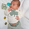 Elijah is registered to the contest to win money with this photo: baby, infant, money, dollar_bills, coins, white_blanket, clothing, striped_pants, sweater, green_clover, pacifier, barefoot, curious, lying_down, date_stamp, indoors, soft_lighting, currency, child, cute