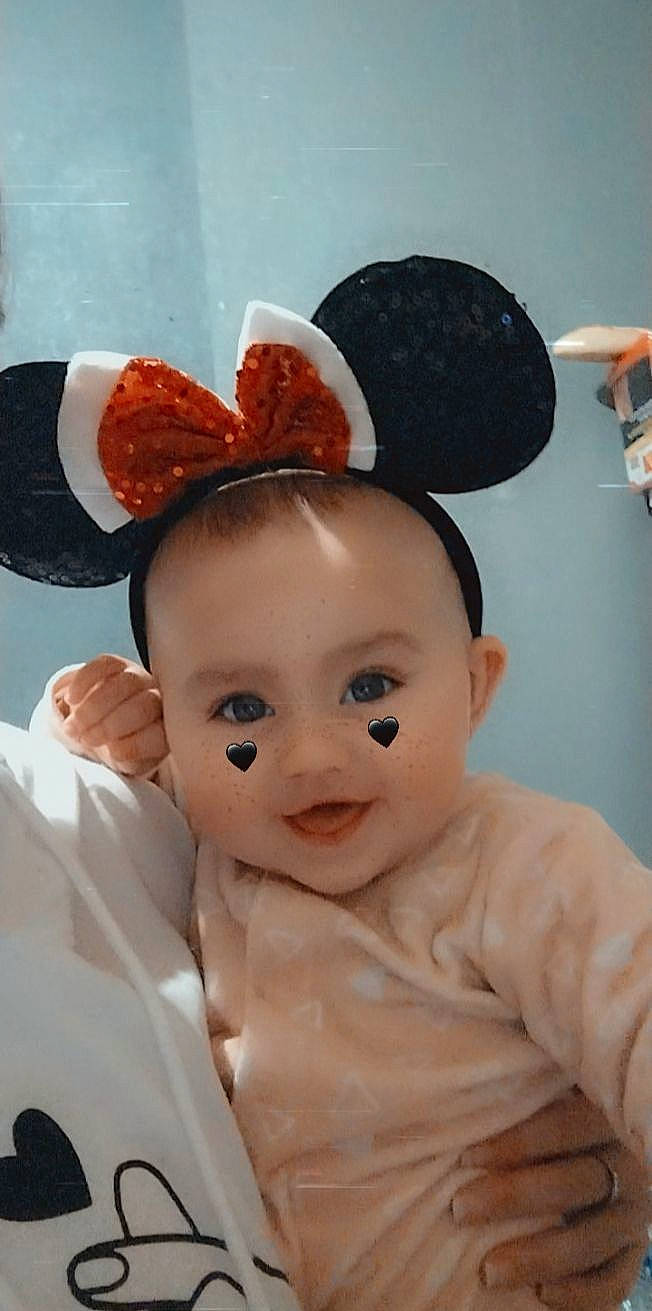 Mia participe au concours pour gagner de l'argent avec cette photo : baby, baby_toddler_clothing, cheek, child, ear, eyelash, fashion_accessory, fun, gesture, hair_accessory, hairstyle, happy, headgear, headpiece, peach, person, room, sleeve, smile, thumb