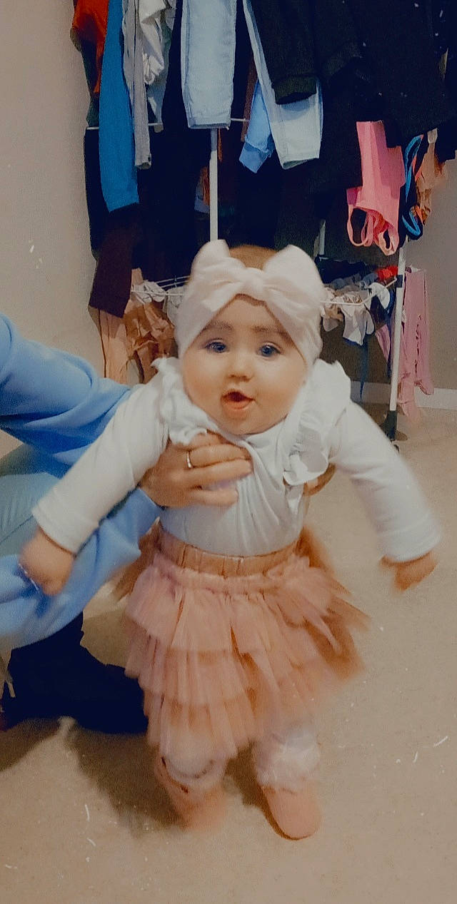 Mia a rejoint le concours — aidez-le/la à gagner de superbes lots ! baby, baby_toddler_clothing, child, costume, costume_hat, day_dress, dress, embellishment, event, fashion_accessory, fun, happy, headwear, pattern, peach, person, pink, ruffle, sitting, sleeve