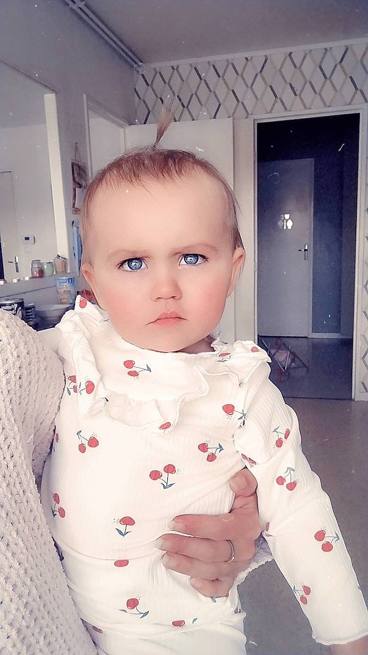 Mia a rejoint le concours — aidez-le/la à gagner de superbes lots ! baby, baby_toddler_clothing, cheek, child, chin, collar, door, eyebrow, face, fashion_design, flooring, happy, lip, neck, nose, pattern, person, sitting, skin, sleeve