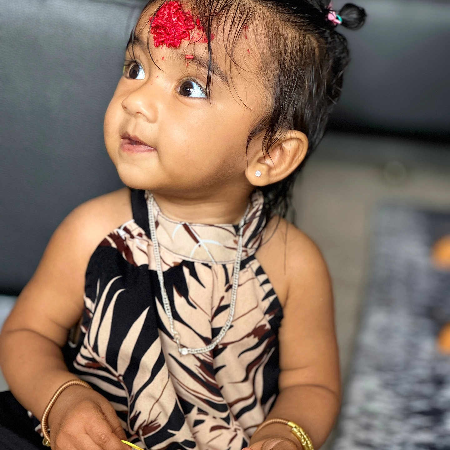 Sanbritti is registered to the contest to win money with this photo: bracelet, child, couch, decorative_mark, dress, eyes, face, girl, hair, hair_tie, hand, holding, indoor, jewelry, necklace, patterned_clothing, portrait, sitting, skin, toddler