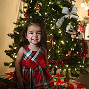 Verity Sol is registered to the contest to win money with this photo: child, girl, christmas_tree, holiday, presents, festive_dress, red_bow, smiling, indoor, decorations, lights, celebration, happy, portrait, toddler, plaid, christmas, gift, holiday_season, festive