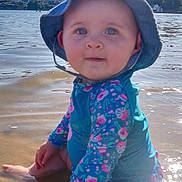 Rose a rejoint le concours — aidez-le/la à gagner de superbes lots ! baby, child, water, beach, sun_hat, swimsuit, sitting, blue_eyes, summer, outdoor, sunlight, reflection, shore, water_surface, person, nature, vacation, holiday, playful, daytime
