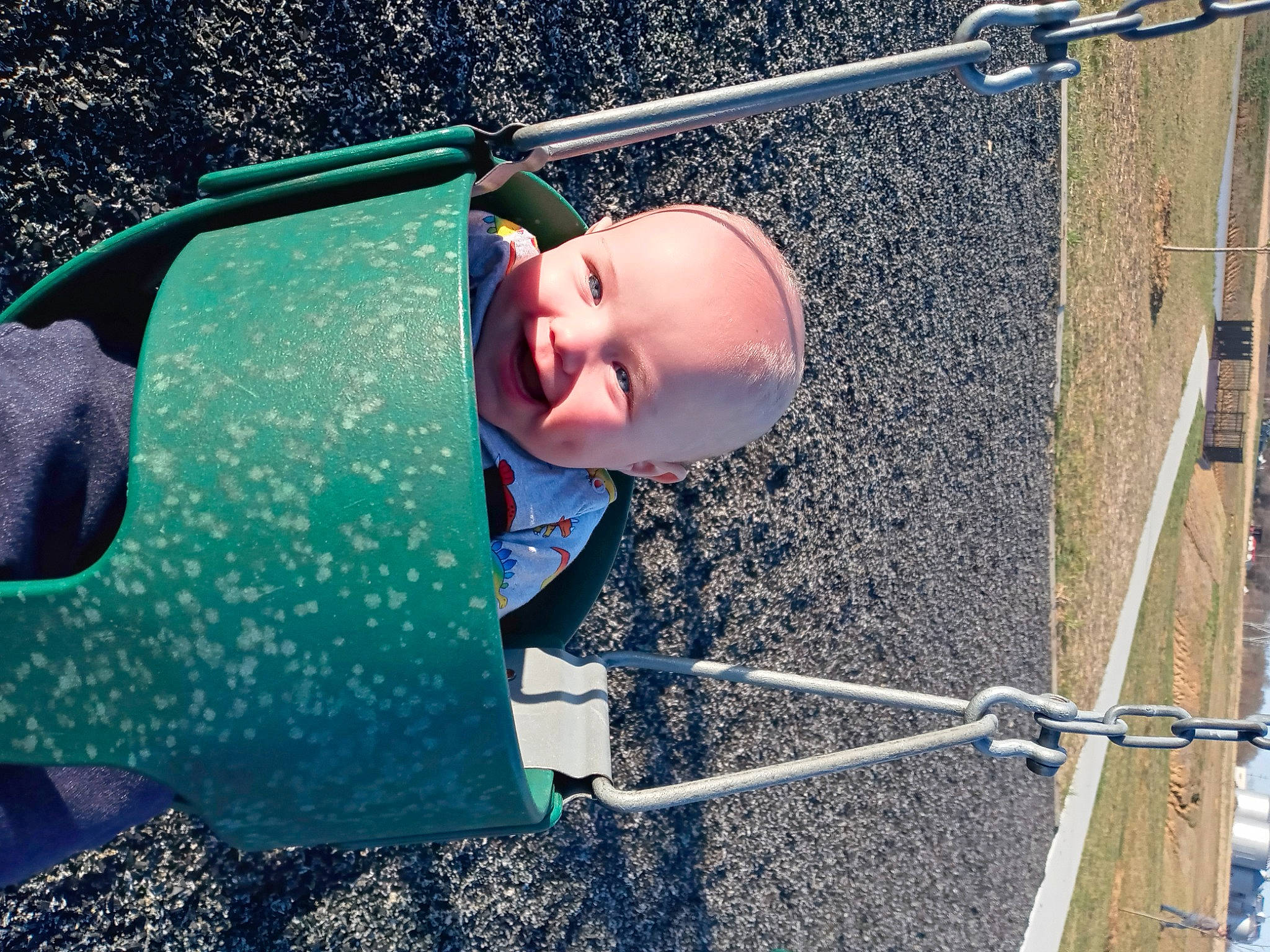 Axl is registered to the contest to win money with this photo: asphalt, baby, child, city, electric_blue, eyewear, fun, grass, green, leisure, outdoor_play_equipment, people_in_nature, person, personal_protective_equipment, play, public_space, recreation, soil, swing, toddler