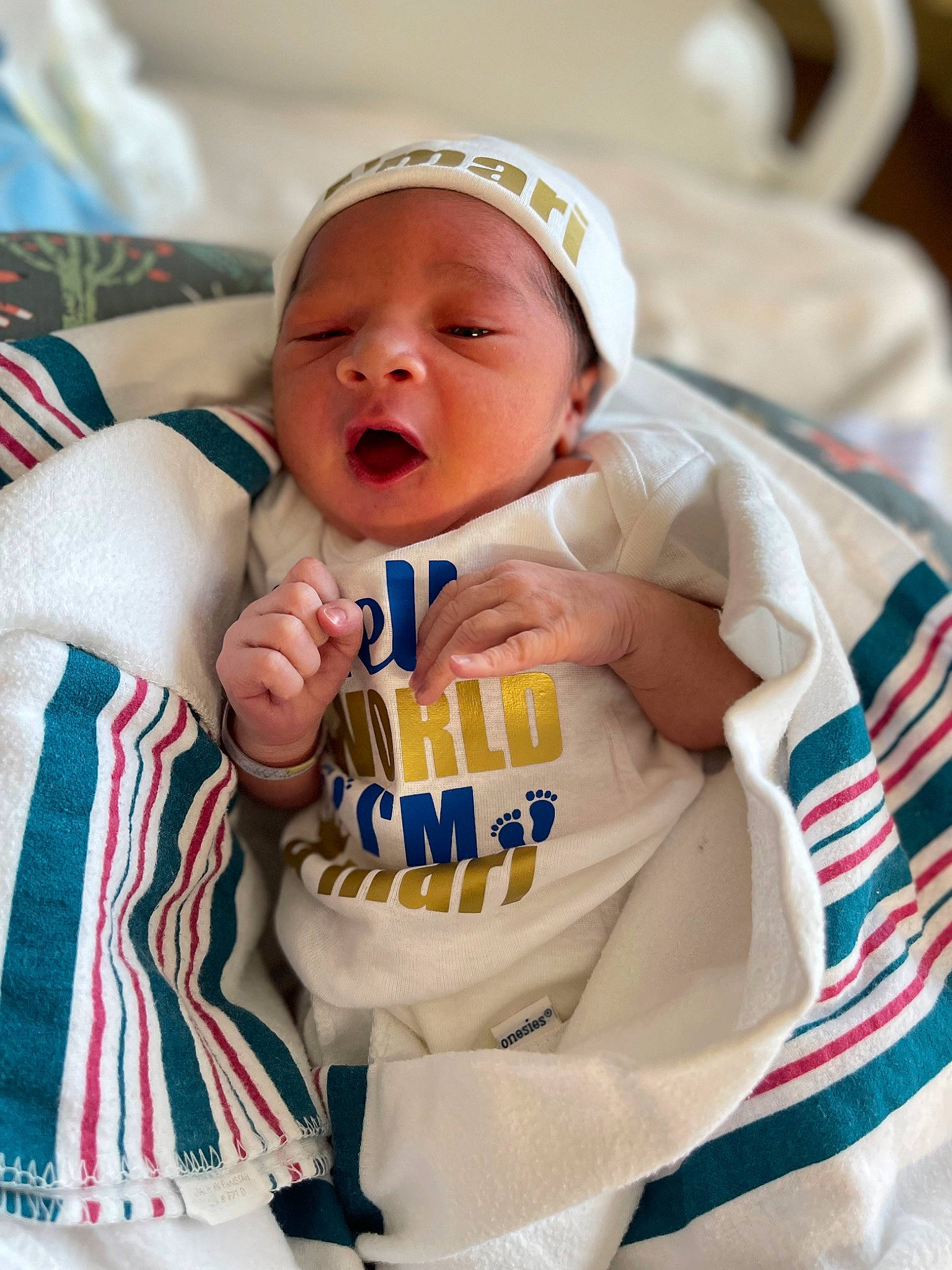 Amari is registered to the contest to win money with this photo: baby, baby_products, baby_toddler_clothing, cap, cheek, child, comfort, face, happy, hat, linens, person, product, room, sitting, sleeve, smile, t_shirt, thumb, toddler