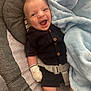 baby, smiling, infant, blanket, mittens, clothing, cushion, happy, child, person, face, indoor, comfortable, soft_texture, striped_socks, seatbelt, portrait, cute, laying_down, warm